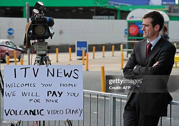 News reporter stands next to a sign on his camera in Dover, in southern England, on April 20 offering money for stories about peoples journey's back...