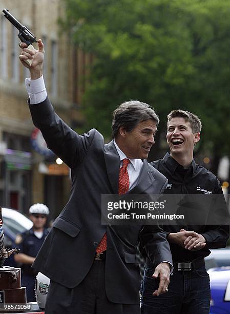 Texas Governor Rick Perry fires a six-shooter pistol in downtown Fort Worth as NASCAR driver Colin Braun looks on April 15, 2010 in Fort Worth, Texas.