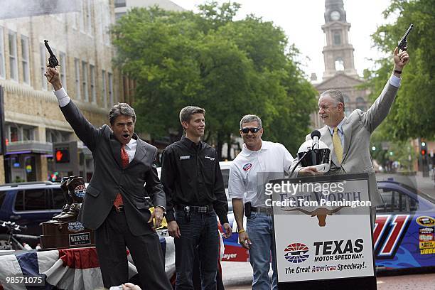 Texas Governor Rick Perry, left, and Fort Worth mayor Mike Moncrief, right, fire six-shooter pistols with NASCAR drivers Colin Braun and Bobby...