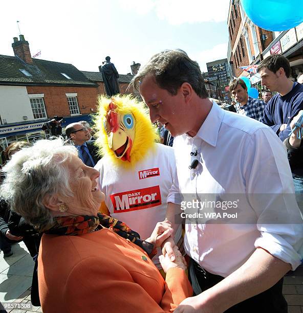 British opposition Conservative party leader, David Cameron speaks with a woman, while a man, dressed as a chicken on behalf of a British newspaper,...