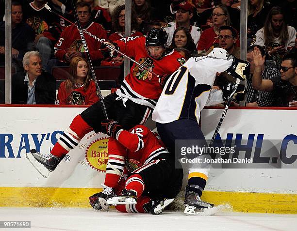Troy Brouwer of the Chicago Blackhawks falls over teammate Kris Versteeg as they battle for the puck with Ryan Suter of the Nashville Predators in...