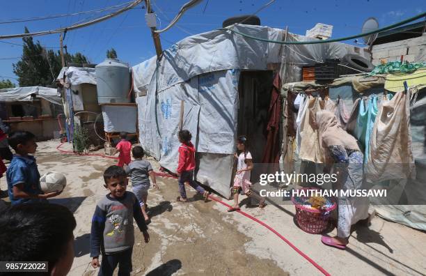Syrian children play as a woman hangs her washing in the narrow alleys of a refugee camp on the outskirts of the town of Zahle in Lebanon's Bekaa...