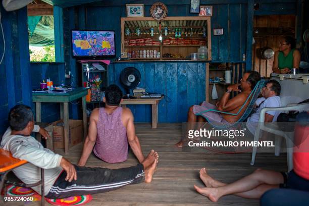 People watch a FIFA World Cup Russia 2018 match between Brazil and Serbia on a TV in Sao Raimundo do Jaraua village, state of Amazonas, Brazil on...
