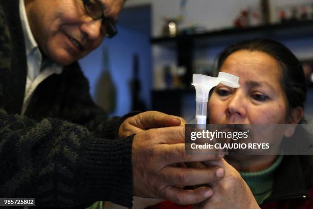 Chilean Josefina Sandoval and her husband hold a test tube containing saliva during an interview with AFP in Santiago, on June 10, 2018. - Josefina...