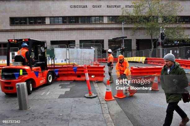 Pedestrian walks past workers at a construction site outside the Circular Quay railway station in the central business district of Sydney, Australia,...