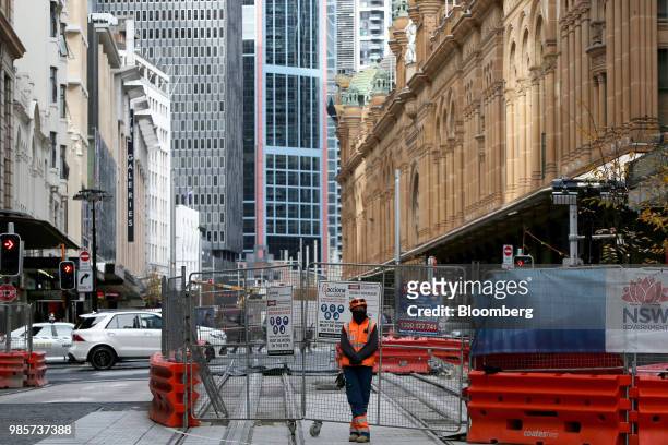 Worker stands next to barricades at a construction site on George Street in the central business district of Sydney, Australia, on Monday, June 18,...