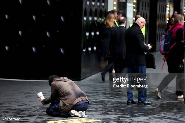 Pedestrians walk past a man begging for money at Market Street in the central business district of Sydney, Australia, on Thursday, June 21, 2018....