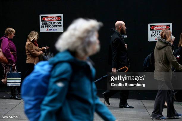 Pedestrians walk past a construction hoarding at Martin Place in the central business district of Sydney, Australia, on Monday, June 18, 2018....