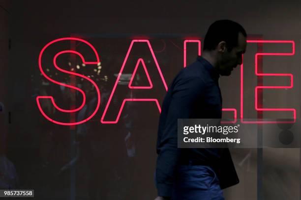 Pedestrian walks past a sale sign displayed in a store window in the central business district of Sydney, Australia, on Thursday, June 21, 2018....