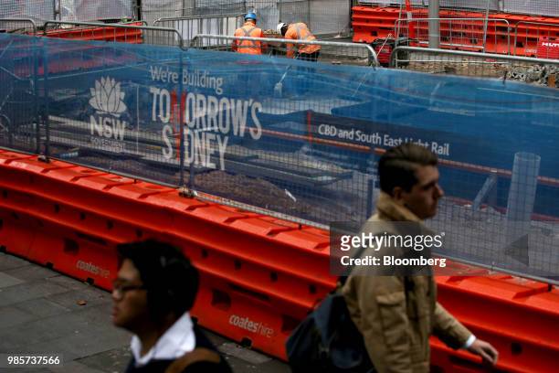 Pedestrians walk past construction barricades on George Street in the central business district of Sydney, Australia, on Monday, June 18, 2018....