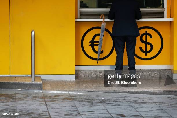 Man stands at a foreign currency exchange booth at a Commonwealth Bank of Australia branch in the central business district of Sydney, Australia, on...