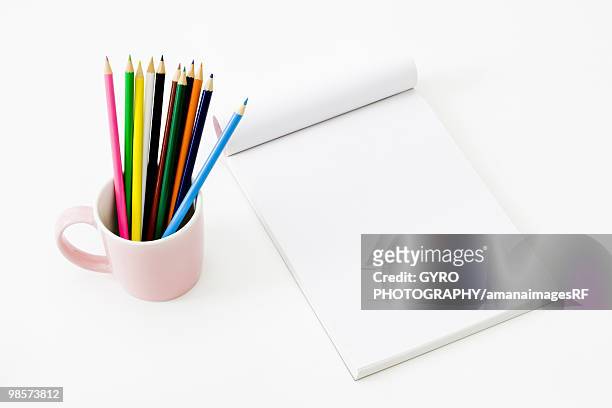 coloured pencils in mug next to blank notepad - creative rf stockfoto's en -beelden