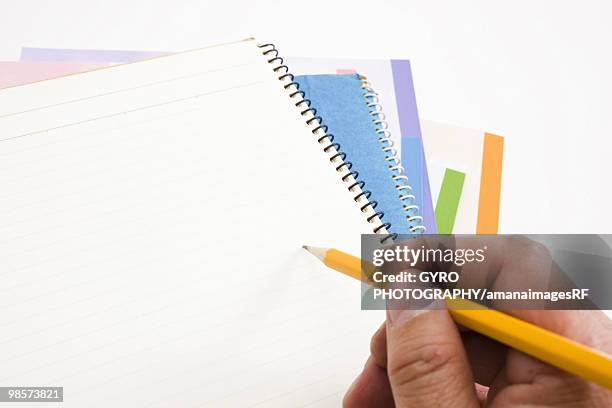 stack of notebooks with person holding pencil over blank page - creative rf stockfoto's en -beelden