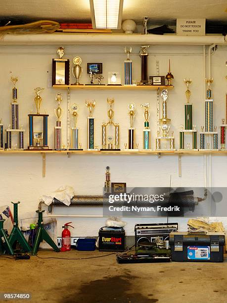 a collection of trophies in a garage. - trophy shelf stock pictures, royalty-free photos & images