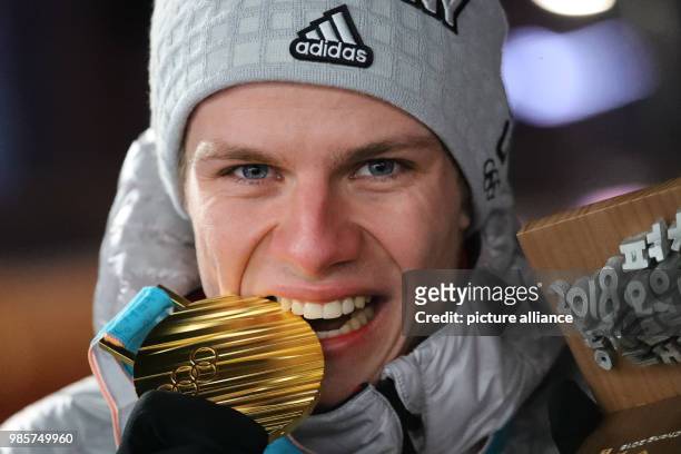 Dpatop - German gold medallist ski jumper Andreas Wellinger bites his medal, after winning the men's normal hill individual ski jumping competition,...