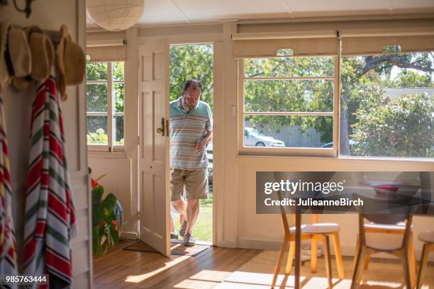 senior man entering in house on sunny day - doorway stock pictures, royalty-free photos & images