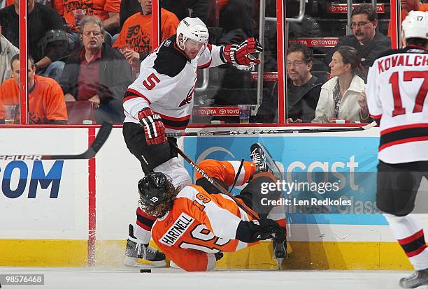 Colin White of the New Jersey Devils drops Scott Hartnell of the Philadelphia Flyers to the ice while battling for the puck in Game Three of the...