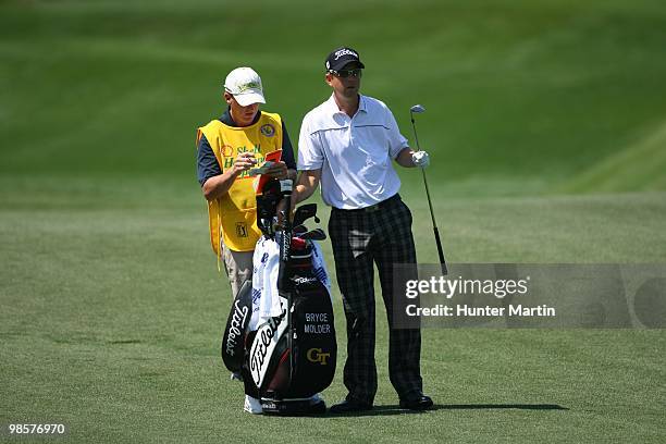 Bryce Molder pulls a club from his bag while alongside his caddie during the third round of the Shell Houston Open at Redstone Golf Club on April 3,...