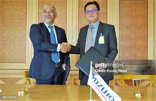 Shojiro Mizoguchi , CEO of Mizuho Bank Berhad, exchanges Islamic finance contract documents with Tan Seng Yang, managing director of...