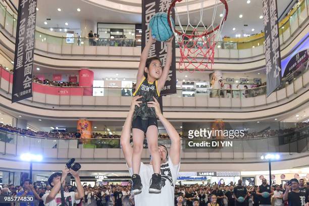 Player Klay Thompson of the Golden State Warriors lifts a kid for a slam in a shopping mall on June 27, 2018 in Taiyuan, China.