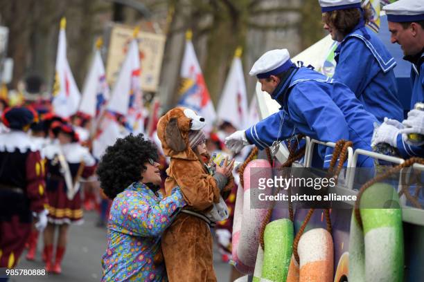 Carnival-goer in sailor costume gives a child sweets during the Rosenmontag carnival procession in Mainz, Germany, 12 Febraury 2018. The...