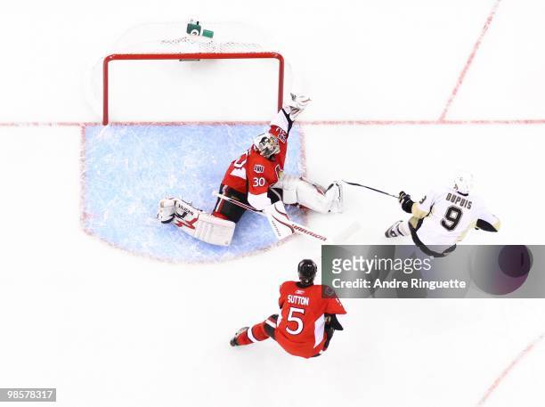 Brian Elliott of the Ottawa Senators makes a glove save on Pascal Dupuis of the Pittsburgh Penguins as Andy Sutton looks on in Game Three of the...