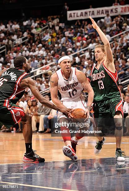 Mike Bibby of the Atlanta Hawks drives to the basket against John Salmons and Luke Ridnour of the Milwaukee Bucks in Game One of the Eastern...