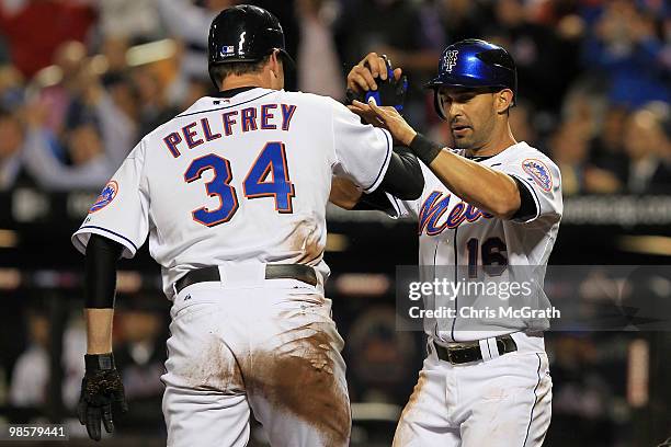 Mike Pelfrey of the New York Mets celebrates with team mate Angel Pagan after they scored of a Jose Reyes triple against the Chicago Cubs on April...