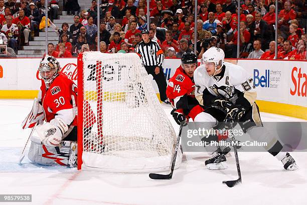 Sidney Crosby of the Pittsburgh Penguins tries to carry the puck to the front of the net with Chris Campoli of the Ottawa Senators in pursuit during...