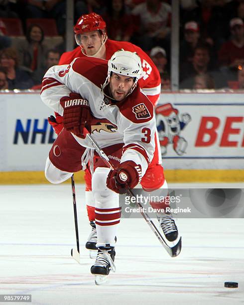 Keith Yandle of the Phoenix Coyotes handles the puck as Darren Helm of the Detroit Red Wings skates behind during Game Four of the Eastern Conference...