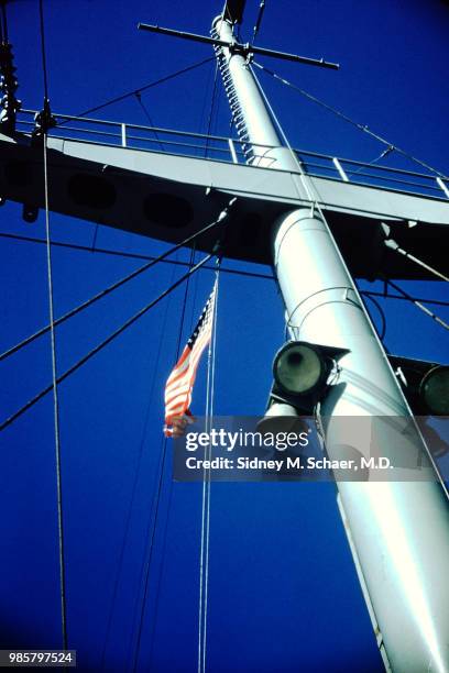 View up the mast of the USNS Marine Serpent transport ship, which flies an American flag, South Korea, January 1952.