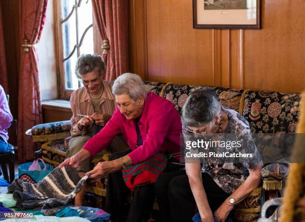 group of senior women with pile finished knitted garments in social knitting circle - old granny knitting stock pictures, royalty-free photos & images