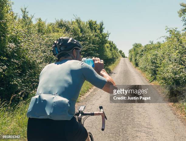 senior cyclist drinking from bidon - spandex stockfoto's en -beelden