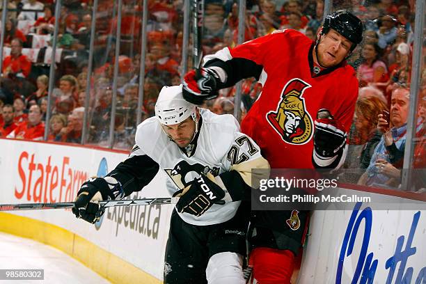 Craig Adams of the Pittsburgh Penguins throws a hit on Andy Sutton of the Ottawa Senators along the end board during Game 4 of the Eastern Conference...