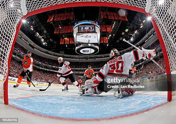 Martin Brodeur of the New Jersey Devils makes a kick save as teammate Mike Mottau and Scott Hartnell of the Philadelphia Flyers wait for a rebound in...