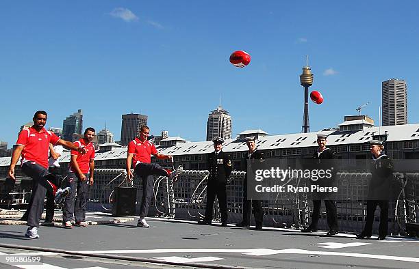 Adam Goodes, Rhyce Shaw and Jesse White of the Swans kick footballs aboard HMAS Sydney during a Sydney Swans AFL Press Conference at HMAS Kuttabul on...