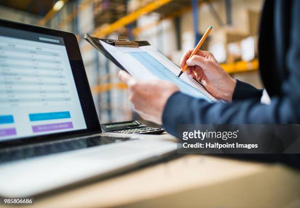 senior warehouse woman manager or supervisor with laptop and clipboard making notes. - belt over top foto e immagini stock