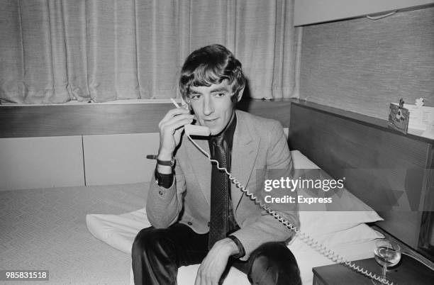 English actor, satirist, writer and comedian Peter Cook using phone in an hotel room, UK, 20th March 1969.