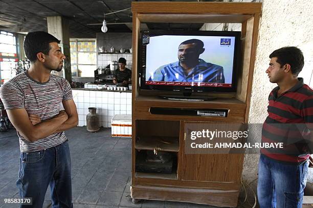 Guests at a coffee shop leave their table to watch a local Iraqi television channel broadcasting a man which Iraqi authorities claim is Abu Omar...