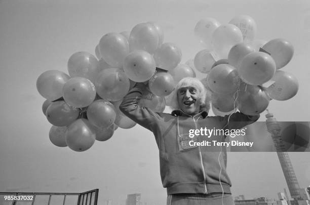 English DJ and television presenter Jimmy Savile pictured releasing balloons from the roof of Broadcasting House in London to celebrate the 5th...