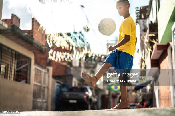 ragazzo brasiliano che gioca a calcio per strada - calcio internazionale foto e immagini stock
