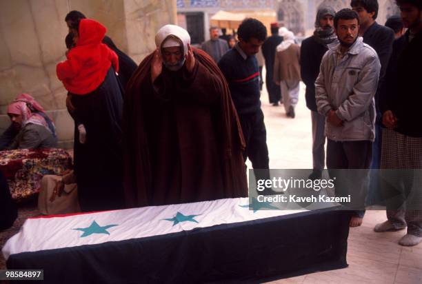 Clergyman prays over the coffin of a victim of Allied forces bombing raids, draped in an Iraqi flag, in the Imam Ali shrine in Najaf, 1st March 1991....