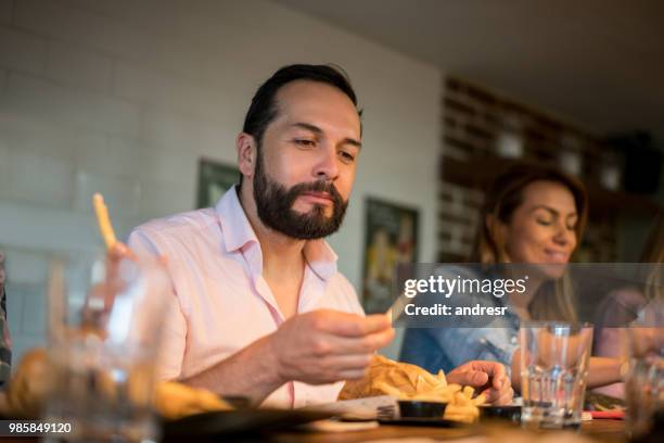 gelukkig latijns-amerikaanse man eten in een restaurant - eating food happy stockfoto's en -beelden