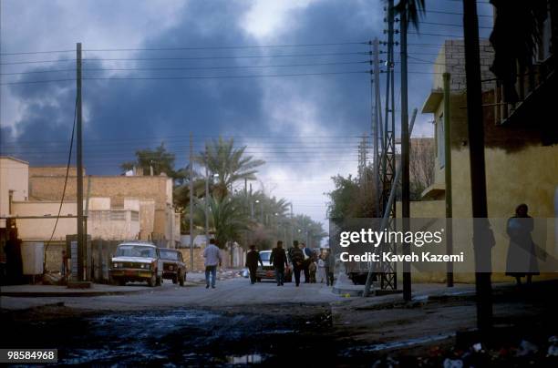 People on the streets of a Baghdad neighborhood with a huge smoke blanket covering the skyline during the Gulf War, 28th February 1991.