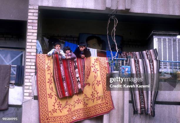 Children look out of their residence in a Baghdad neighborhood with a picture of Saddam Hussein in the background during the Gulf War, 28th February...