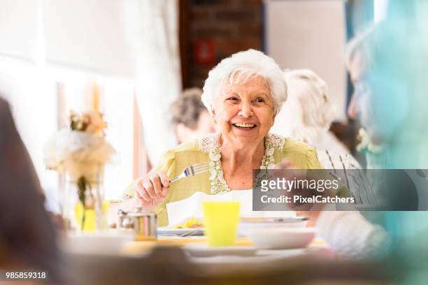 ritratto di una donna anziana sorridente che pranza con gli amici - tipo di cibo foto e immagini stock