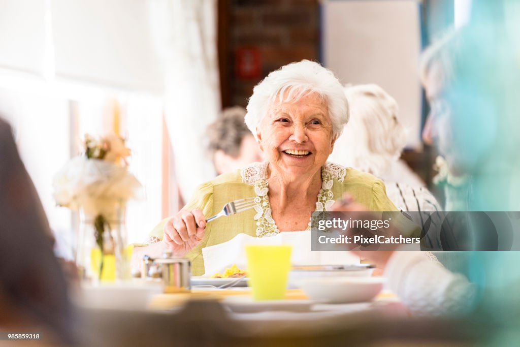 Portrait of a smiling senior woman having lunch with friends