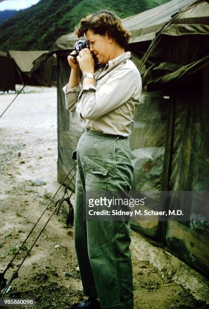 View of American military anesthetist Millie Rush, of the 8063rd MASH , as she takes photographs outside a US Army tent, South Korea, January 1952.