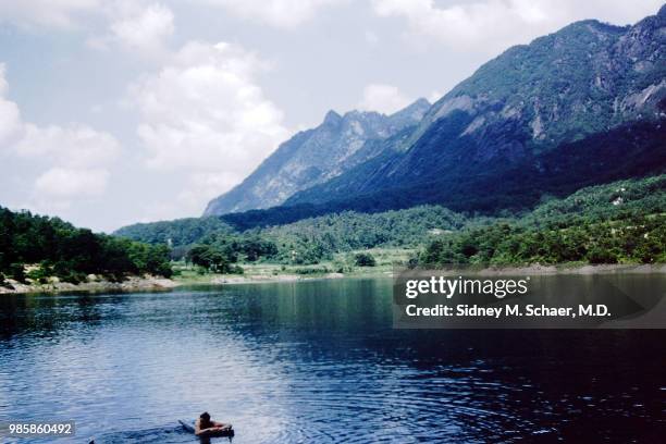 Elevated view of an unidentified US soldier as he lies on an inflatable raft in a mountain reservoir, South Korea, January 1952.