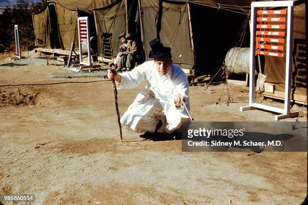 Portrait of American military surgeon Captain Sidney Schaer , of the 8063rd MASH , dressed in traditional Korean clothing as he smokes a long pipe...